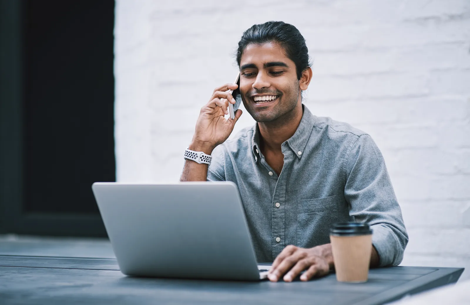 Pengasas muda tersenyum semasa panggilan telefon di laptopnya